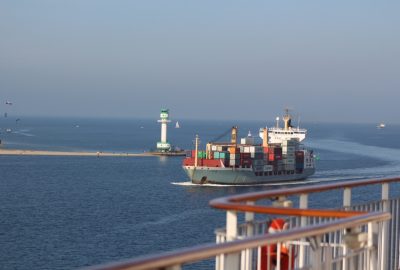 Un petit porte-containeurs passe entre le phare de Friedrichsort et le ferry Color Magic. Photo © André M. Winter