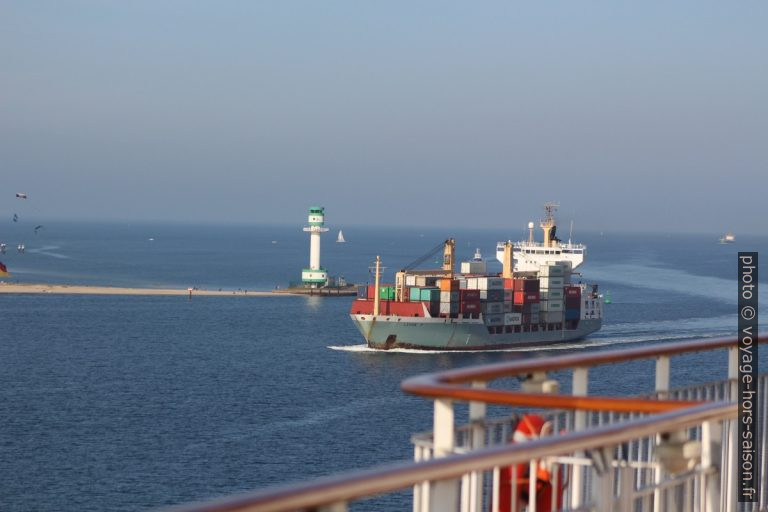 Un petit porte-containeurs passe entre le phare de Friedrichsort et le ferry Color Magic. Photo © André M. Winter