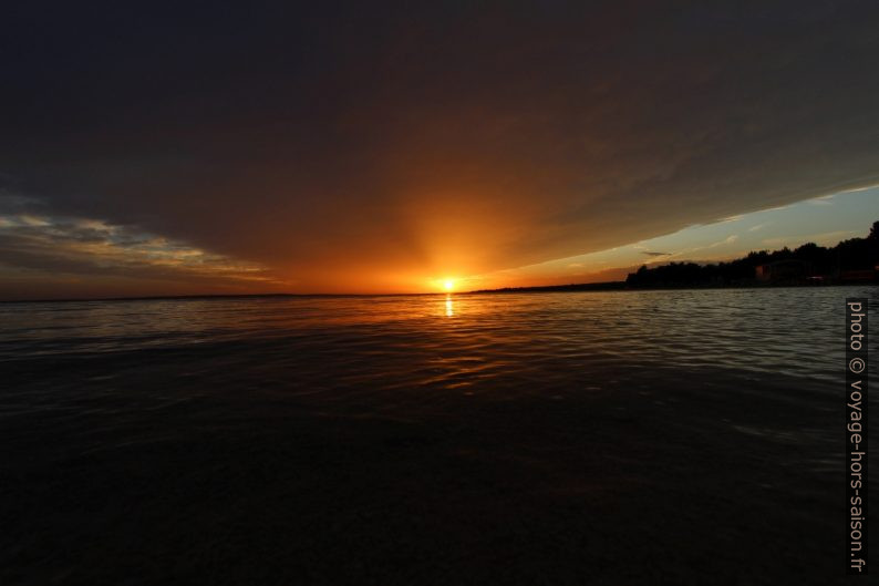 Le soleil passe sous le gros nuage avant de se coucher. Photo © André M. Winter