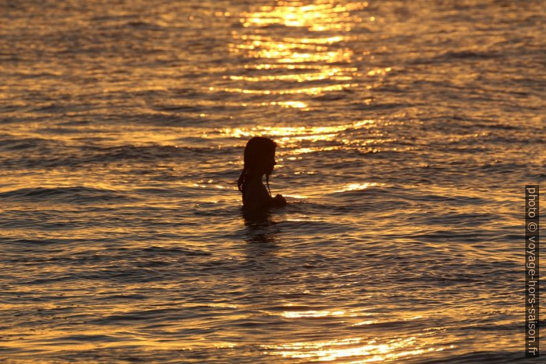 Une fille dans l'eau sous le coucher du soleil. Photo © André M. Winter