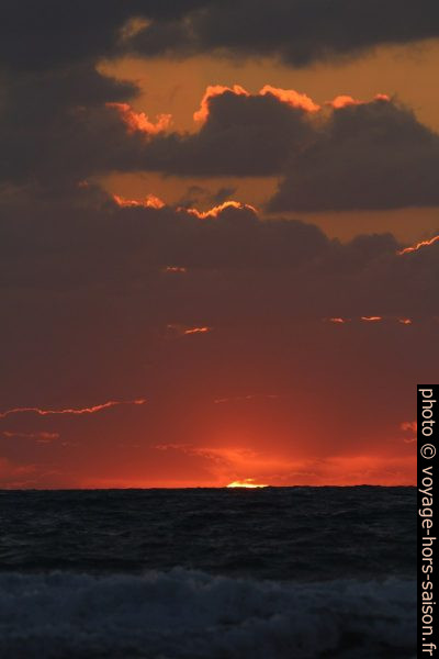 Dernier morceau du disque du soleil au-dessus de la mer. Photo © André M. Winter