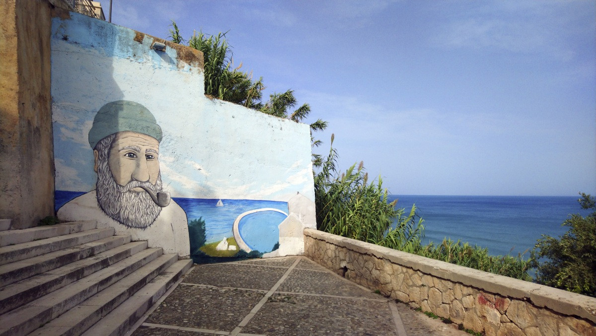 Escalier avec un mur peint d'une tête de marin à Rodi Garganico. Photo © André M. Winter