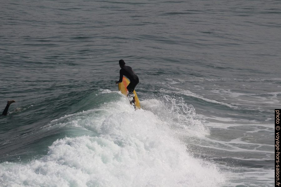 Un surfeur à planche jaune au dernier bout de sa vague. Photo © André M. Winter