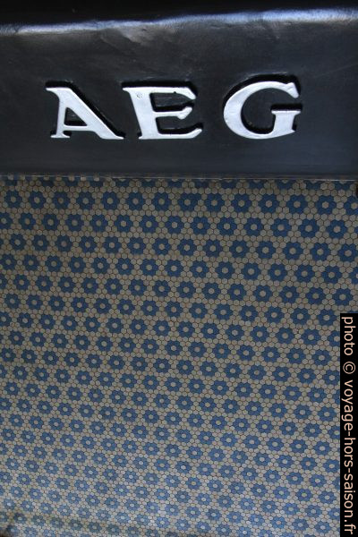 Logo de AEG et carrelage du sol bleu et blanc hexagonal. Photo © André M. Winter