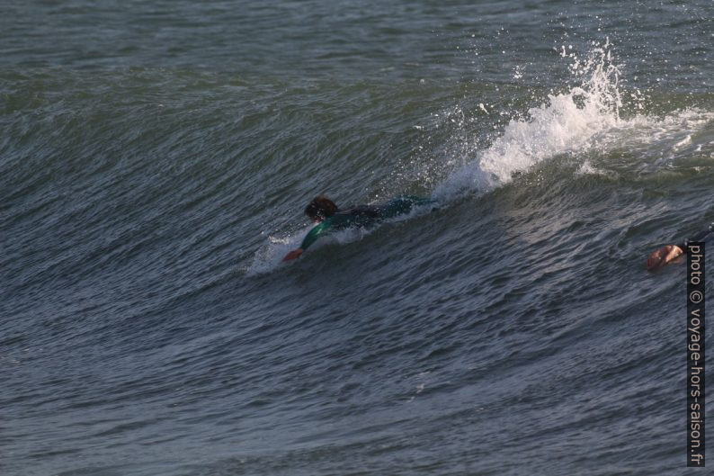 Un surfeur prend de l'élan en ramant. Photo © André M. Winter