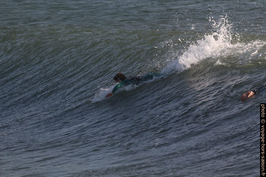 Un surfeur prend de l'élan en ramant. Photo © André M. Winter