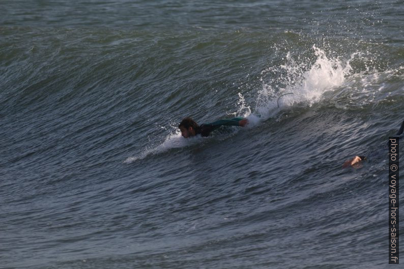 Un surfeur prend de l'élan en ramant. Photo © André M. Winter