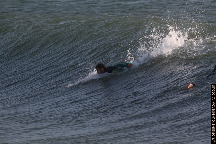 Un surfeur prend de l'élan en ramant. Photo © André M. Winter