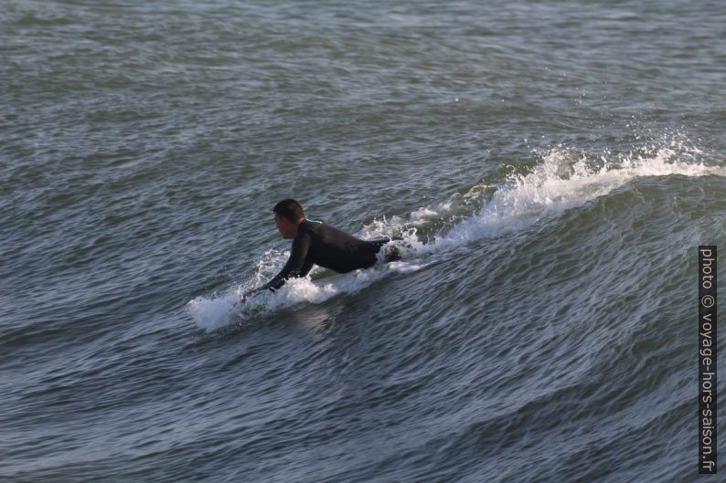 Un surfeur prend de l'élan sur la vague. Photo © André M. Winter