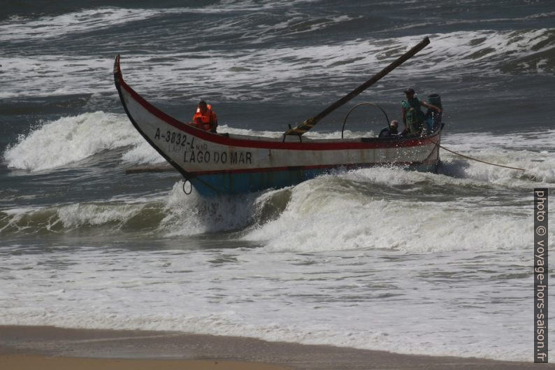 La barque de pêcheurs Lago do Mar portée par une vague vers la plage. Photo © André M. Winter