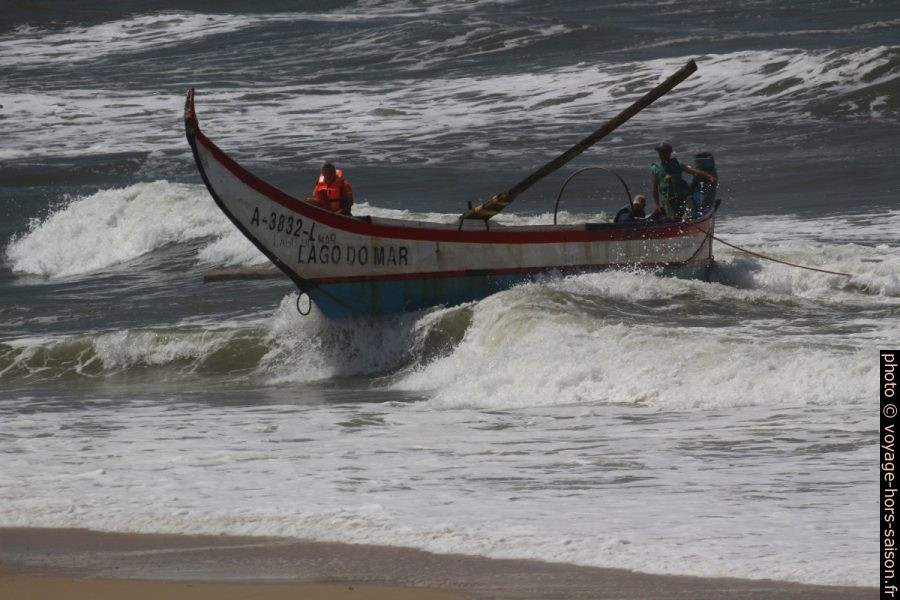 La barque de pêcheurs Lago do Mar portée par une vague vers la plage. Photo © André M. Winter