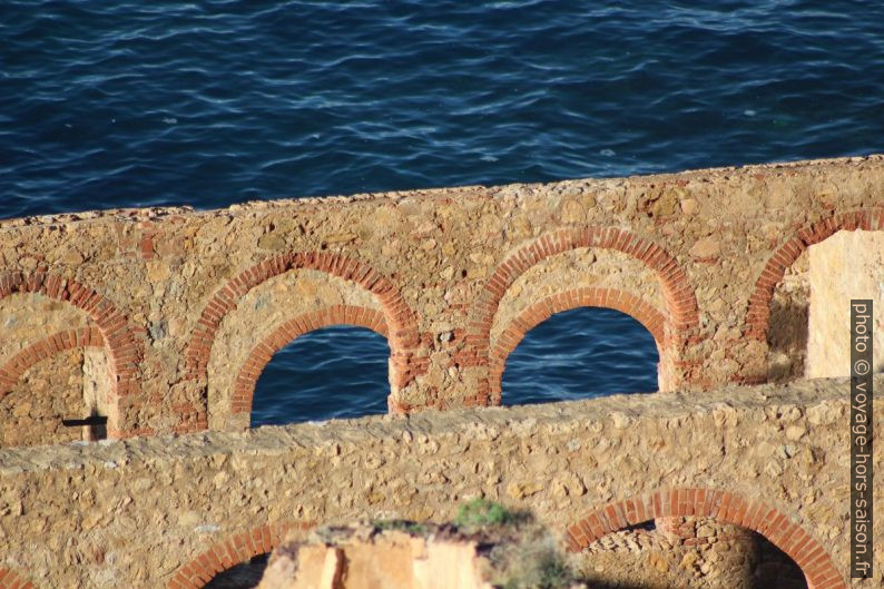 Murs et arcs de la Laverie Larmamora devant la mer bleue. Photo © André M. Winter
