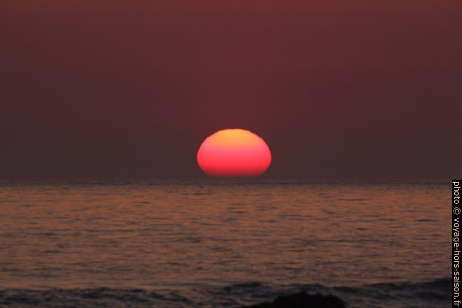 Le disque du soleil plonge d'un tiers dans la mer. Photo © André M. Winter