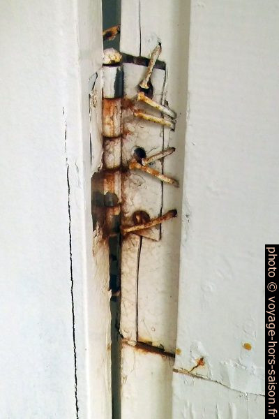 Charnière de porte fixée avec des clous dans du bois pourri. Photo © André M. Winter