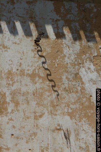 Ombre et gnomon en forme de serpent d'un cadran solaire effacé. Photo © André M. Winter