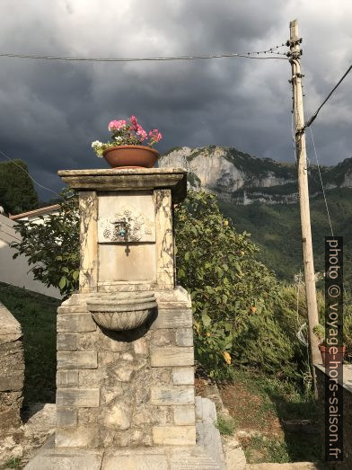 Une fontaine, le ciel gris et le Monte Nona. Photo © Alex Medwedeff