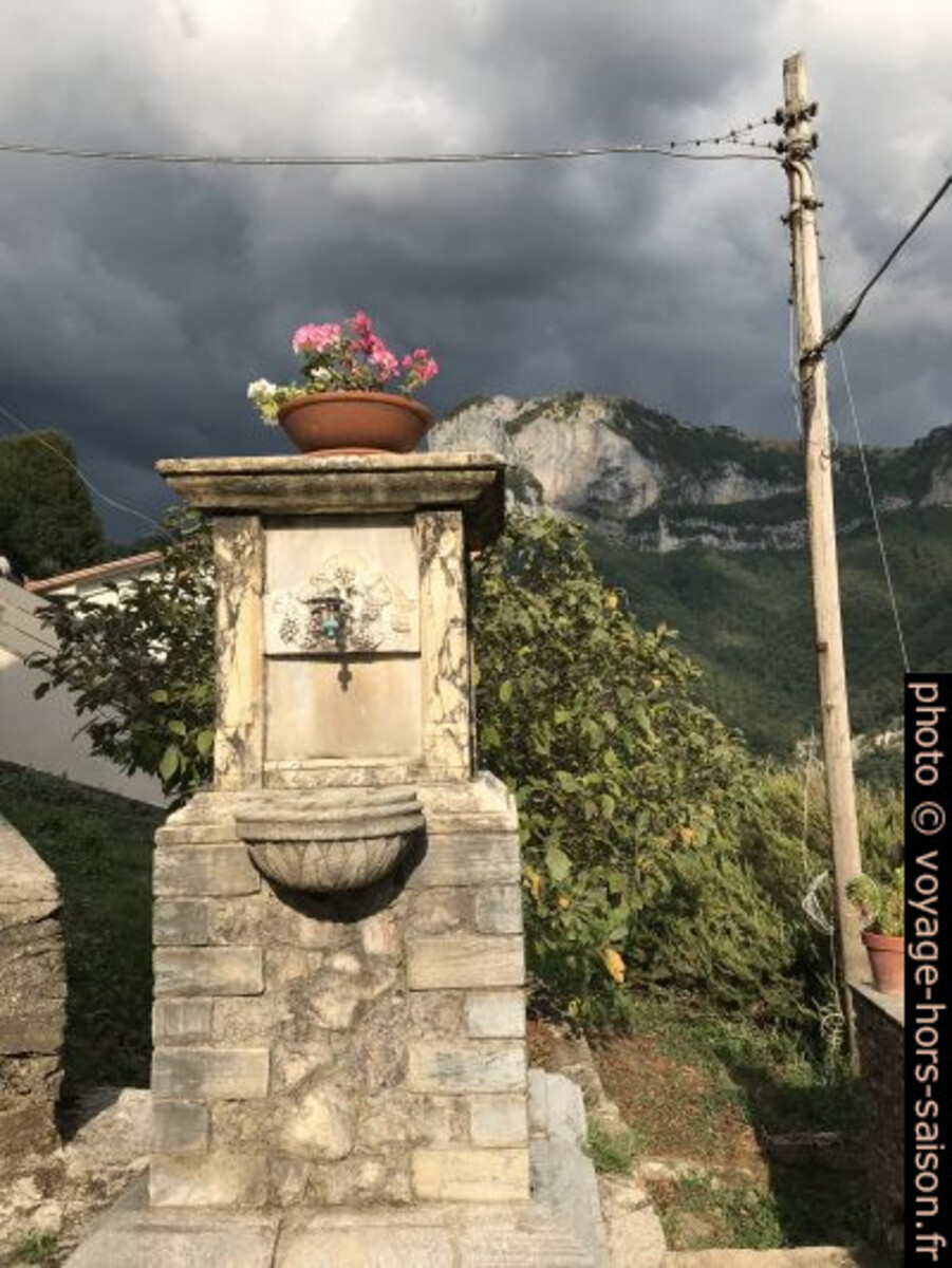 Une fontaine, le ciel gris et le Monte Nona. Photo © Alex Medwedeff